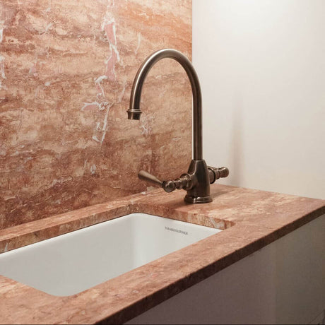 Kitchen sink with bronze faucet against a marble backsplash
