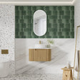 Bathroom with green tiled wall, wooden vanity, and white sink.
