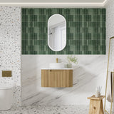Bathroom with green tiled wall, wooden vanity, and white sink.