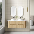 Bathroom with wooden vanity, double sinks, and two oval mirrors.