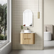 Bathroom with wooden vanity, round mirror, and tiled wall.