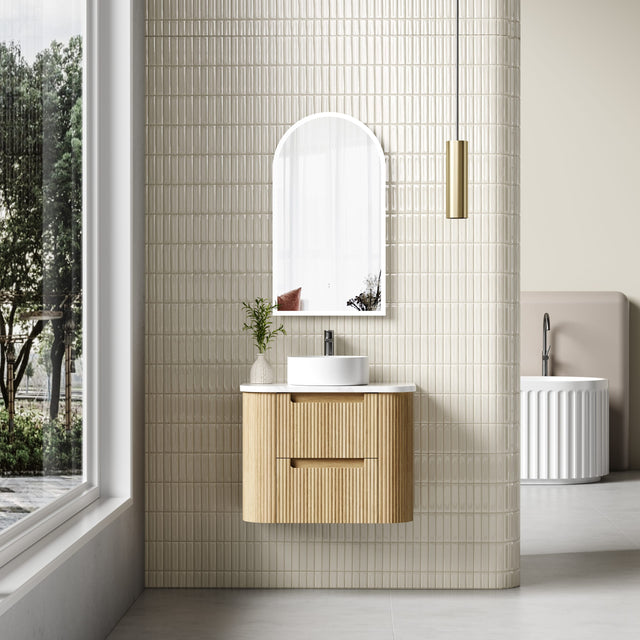 Bathroom with wooden vanity, round mirror, and tiled wall.