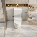 A modern white ceramic one-piece toilet centered in a luxurious bathroom setting with marble walls and floor, a gold-framed shower door, and a matching marble vanity.