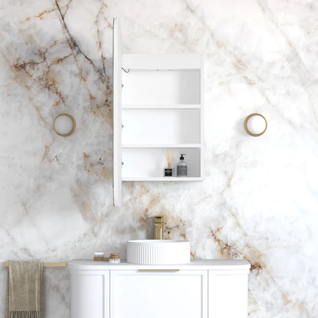 A white wall-mounted bathroom cabinet with three shelves, shown open with a sink, gold faucet, and marble-patterned wall behind it.